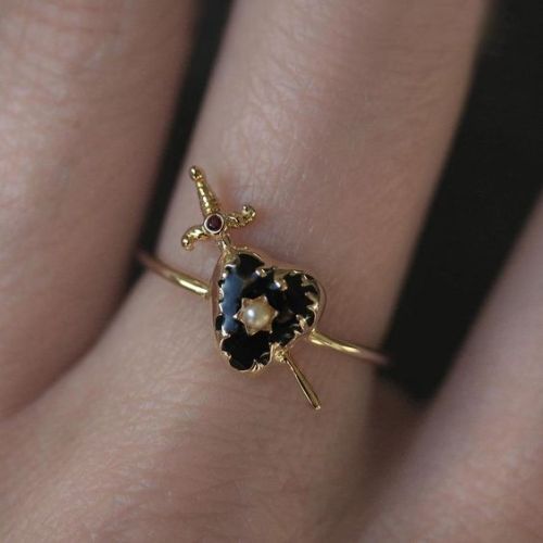 beanspirit:waywitchy: Heart and Sword Ring  [ID: A gold ring with a black, heart-shaped gem in the m