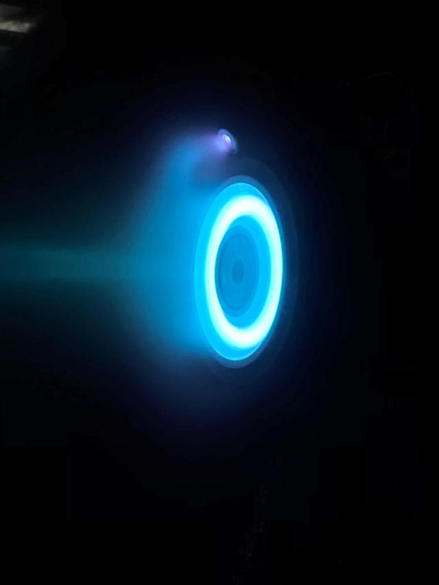A Hall-effect thruster emits a blue glow trailing behind the spacecraft. Credit: NASA/JPL-Caltech
