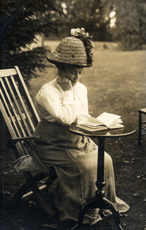 foundinanattic:Woman in an elaborate hat reading outside, date unknown