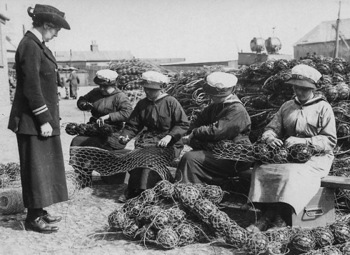 Workers wiring floats together to make “mine nets” (Britain, WW1).These large mesh wire nets h