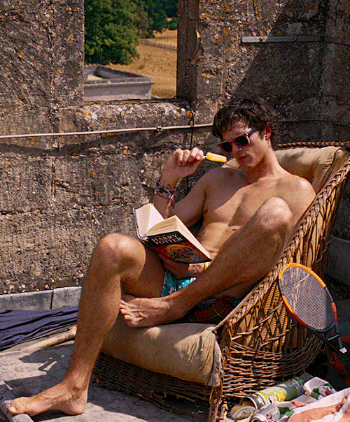 [Sunny day on rooftop of Saltburn Castle] A shirtless Felix Catton (Jacob Elordi) is seated tucked into an antique bamboo lounge chair. Wearing a red-framed rayban sunglasses, he looks engrossed in a Harry Potter book while he takes a suck on a popsicle with his right hand. 

Saltburn (2023) dir. Emerald Fennell 

[Gif Creator/Editor: k-wame.tumblr.com]
