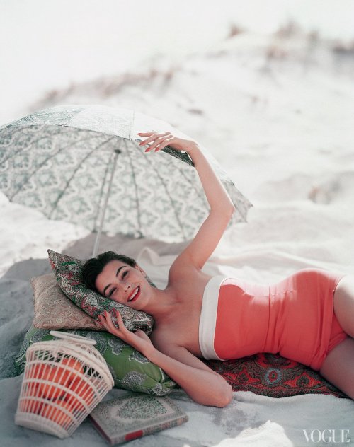 Ann Gunning posing in swimsuit with book and oranges. Vogue, July 1954. Photograph by Karen Radkai.G