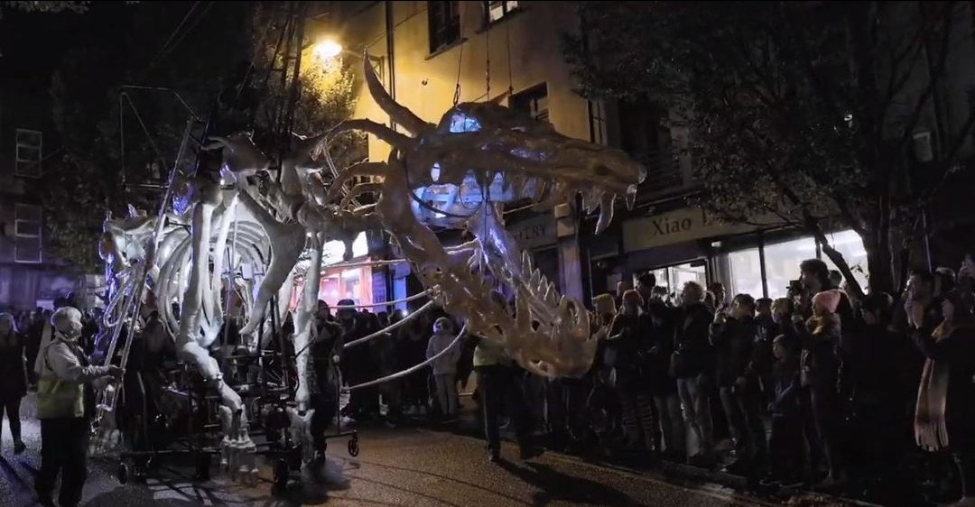 photo of a giant skeletal dragon puppet in a parade in a city at night