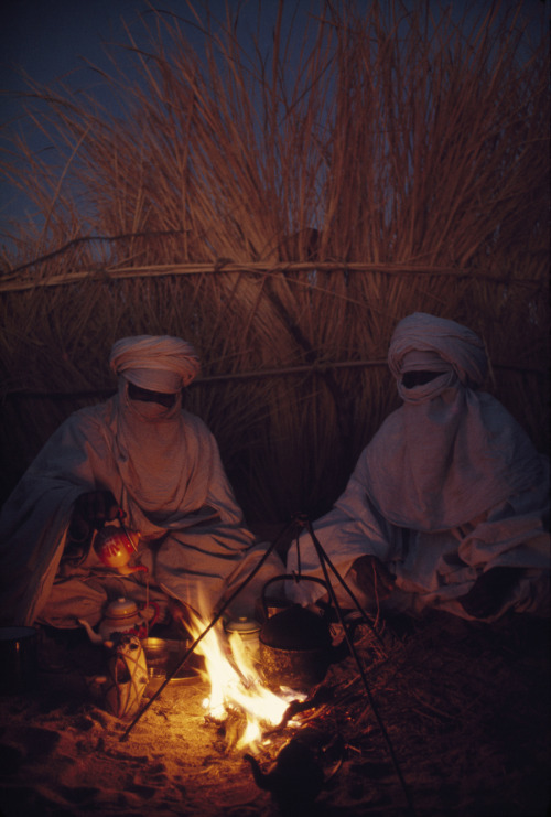 Tuareg goatherds drink tea in their desert shelter at Hassi Izernene, August 1973.Photograph by Thom