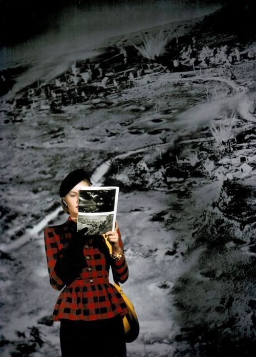 Model reading about war and viewing photographs in front of an enlarged photograph showing bombing, 