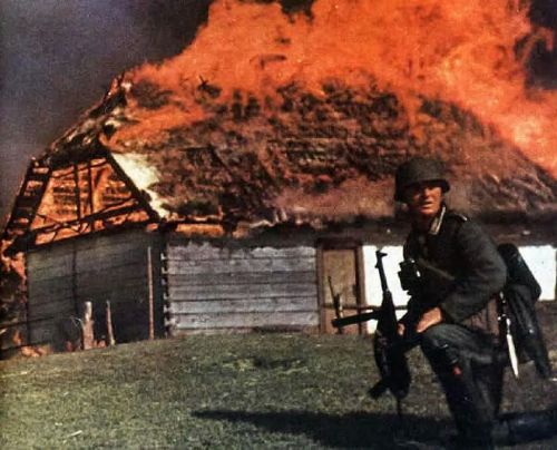deutschland-obsiegt: A German soldier pauses near a burning barn in Russia.
