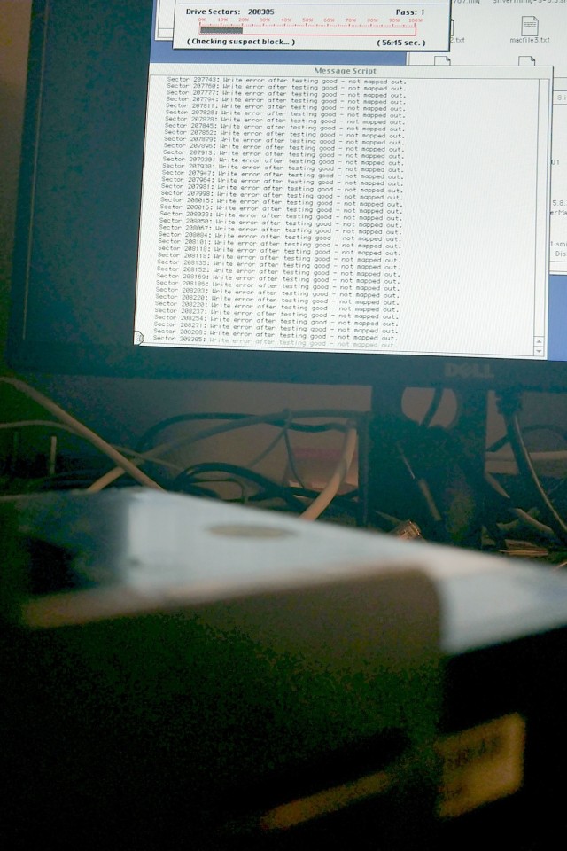 Background: screen image showing thousands of drive write errors. Foreground, blurred: the failing hard drive.