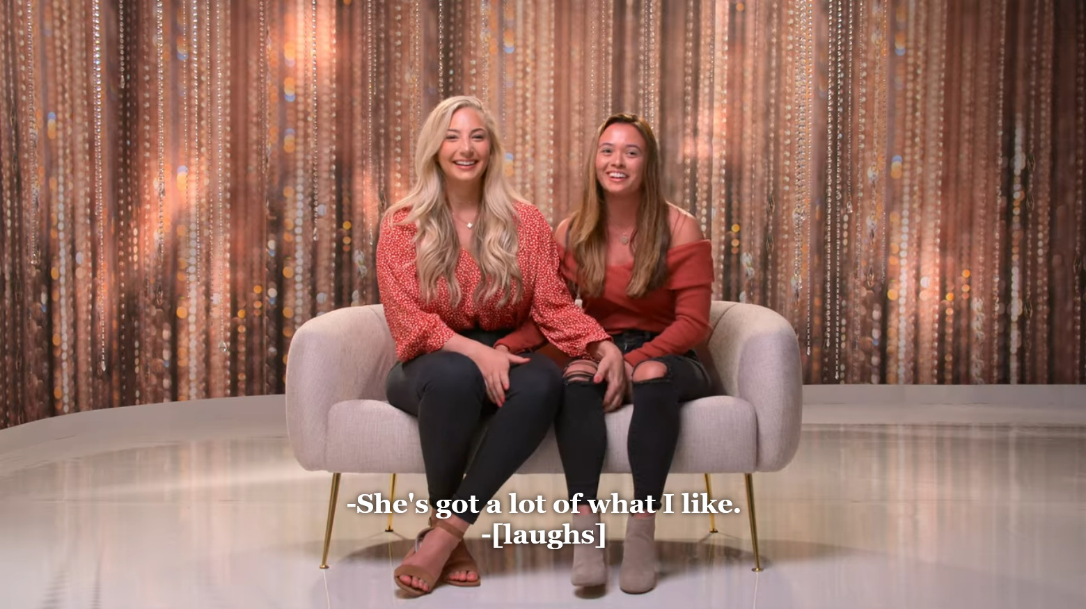 Lexi on left and Rae on right sitting at the confessional couch. Rae says "She's got a lot of what I like," referring to Lexi's bra size, and they laugh.