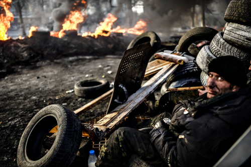 An anti-government demonstrator sit behind a barricade on February 21, 2014 at the Independent squar