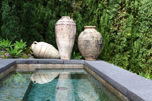Stone spa accented with ancient Greek and Roman urns and a drift of Agave attenuata. Photo by Doug J