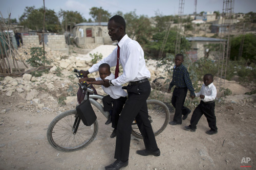 A father walks with his three sons to a Saturday morning church service in Canaan, Haiti on June 20,