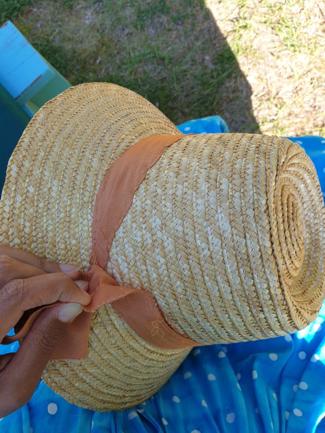 a bonnetshaped sunhat with an orange ribbon in the process of being ripped off