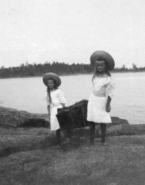 Little Grand Duchesses Olga and Tatiana Nikolaevna Romanov carrying something together.