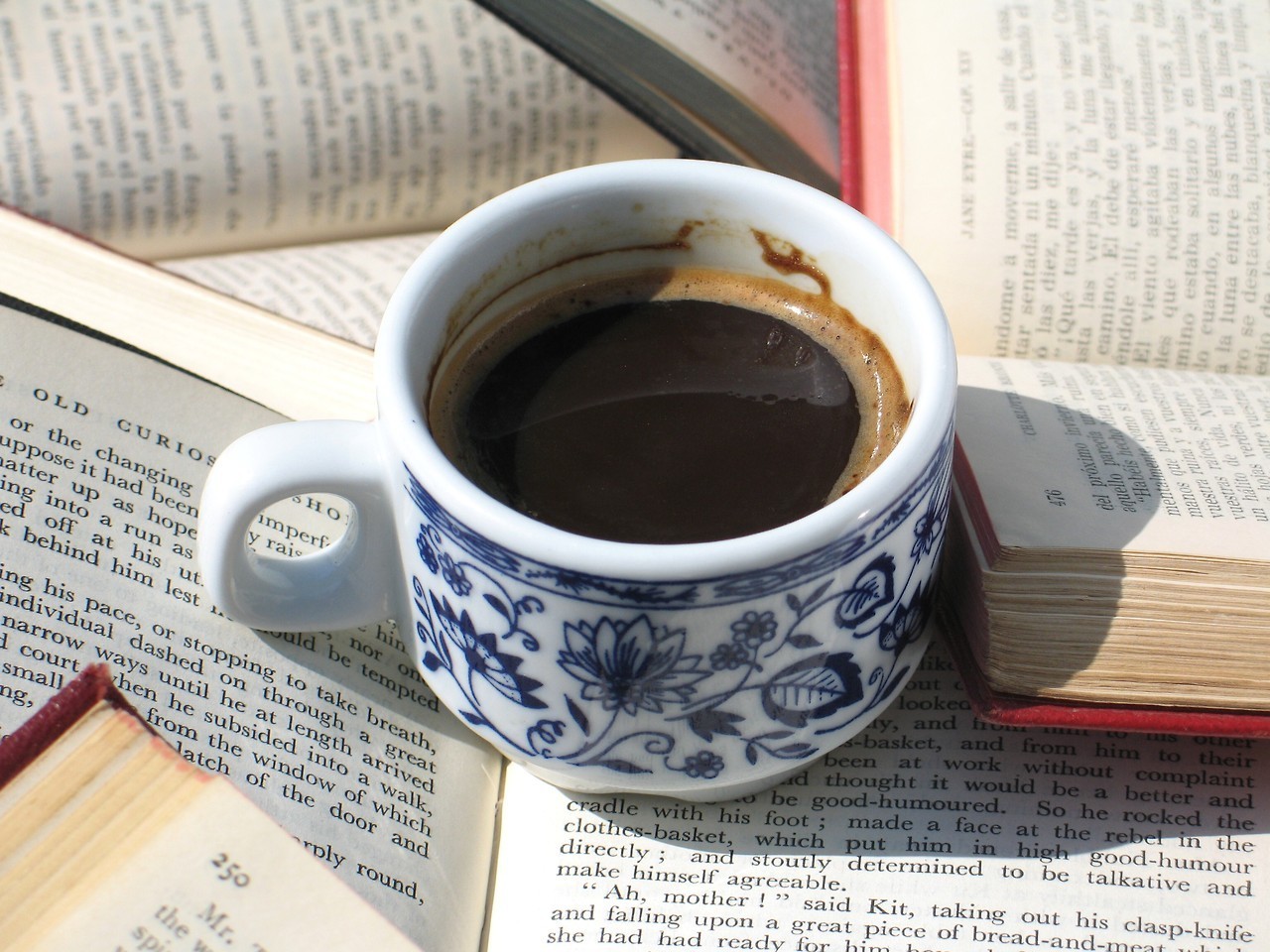 a cup of coffee sits in the middle of a pile of books.jpg
