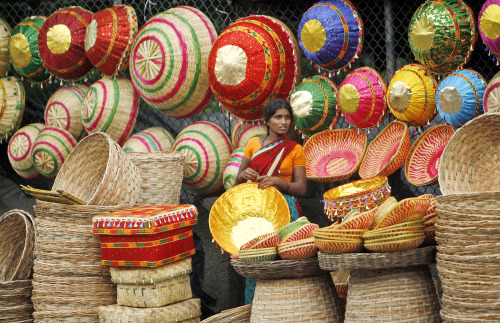 A woman waits for customers at her roadside stall selling cane baskets in Hyderabad, India on August