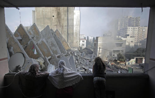 A Palestinian family looks from a window to the rubble of the collapsed 15-story Basha Tower followi