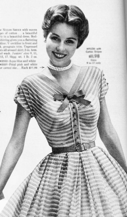 Model wearing a striped dress with a bow neck, 1950s.