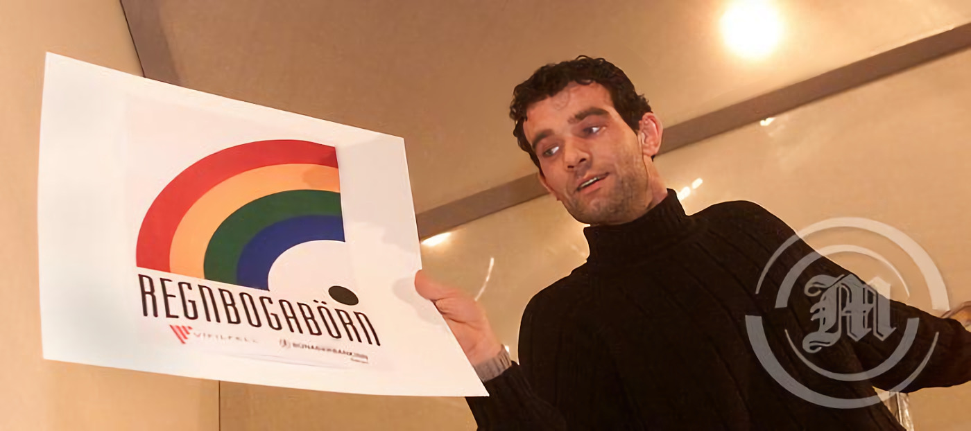 Stefán Karl holding a paper sign with an early logo of Rainbow Children