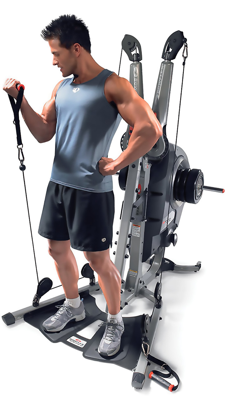 A man uses the Bowflex Revolution exercise machine. He is holding a strap attached to a cable. Credit: Bowflex