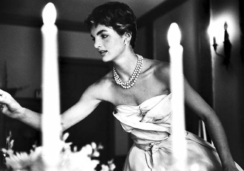 thekennedyclan: 1953, Jackie Kennedy lights candles for a dinner with friends, months after her wedd