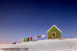 unrar:  Two people hanging out laundry near a small green cottage in Greenland, by Thomas Nebbia.   