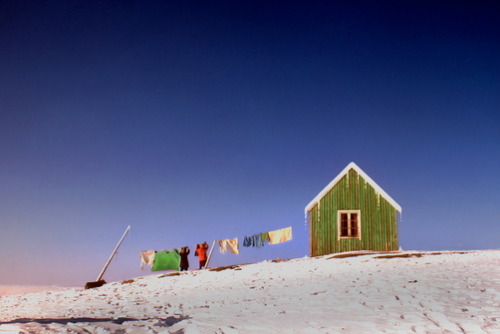 unrar - Two people hanging out laundry near a small green cottage...