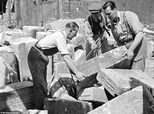 Three workmen using a measuring tape to determine the size of stones as they remove them from the ru