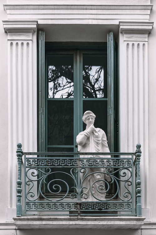 A marble statue in Athens overlooking the street from the balcony.