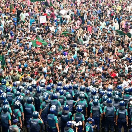 a large number of student protestors facing a wall of policemen in Dhaka, Bangladesh