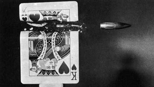 retroreverbs:  High speed photography. A flash of about 10 microseconds from a Xenon lamp illuminates the subject at the appropriate moment. Thus a camera with its shutter open records the rifle bullet having cut the playing card. 