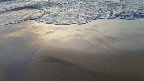 Reflet d'un soleil couchant dans la douceur du sable blanc.