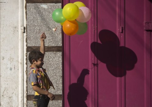 A Palestinian boy plays with balloons as families leave their homes in Gaza City’s Shejaiya ne