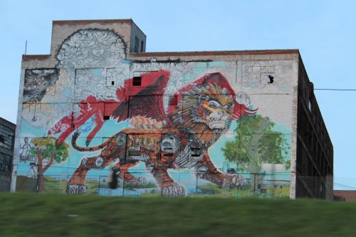 blondebrainpower:  Mural in Detroit, Michigan by Kobie Soloman off of I-75       This painting was executed by one person, using an 85 foot articulating boom, and is a portrait of Detroit’s past, present, and future. The lion contains elements