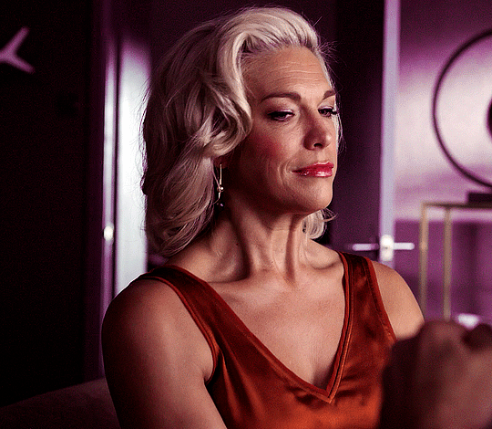Img: Rebecca glances suggestively down and to the side while wearing her orange tank top
