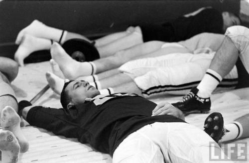 College football players in repose before a Minnesota-Iowa game, 1960. Three of the players are hang