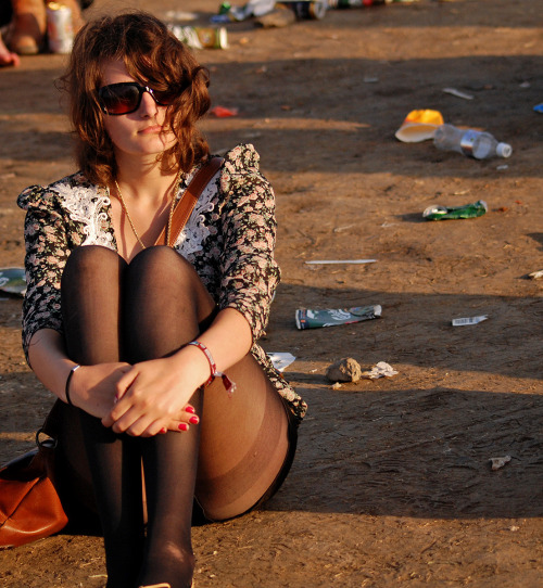 Sexy lady in black pantyhose sat on the mud of a festival. Woman in pantyhose