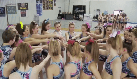 A cheerleading team puts their hands together