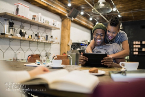 Smiling couple using digital tablet in cafe