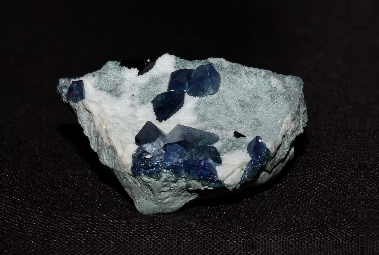 arockmaniac:  Gemmy benitoite crystals with a tiny crystal of neptunite on a matrix