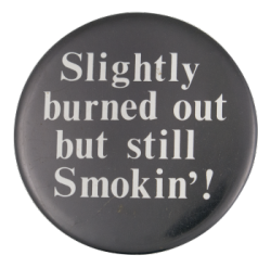 a black pin with white text that reads 'Slightly burned out but still Smokin'!'