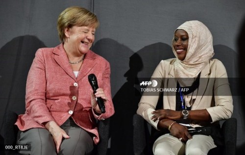 German Chancellor Angela Merkel chats with Nyima Jadama from Gambia during a meeting of refugee stud