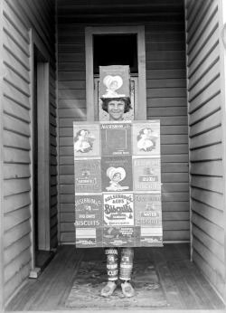 Adam MacLay - Outdoor portrait of an unidentified child in fancy dress as a &lsquo;Aulsebrook Biscuit&rsquo; box, ca. 1915-20.
