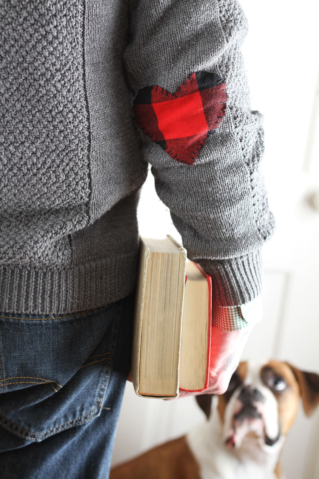 A red flannel heart-shaped elbow patch on a gray knitted sweater.