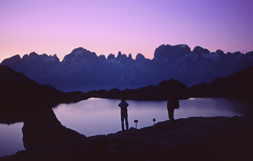 Some hikers watch the sun sink behind the Brenta Dolomites from Cornisello Lake.Italy1988