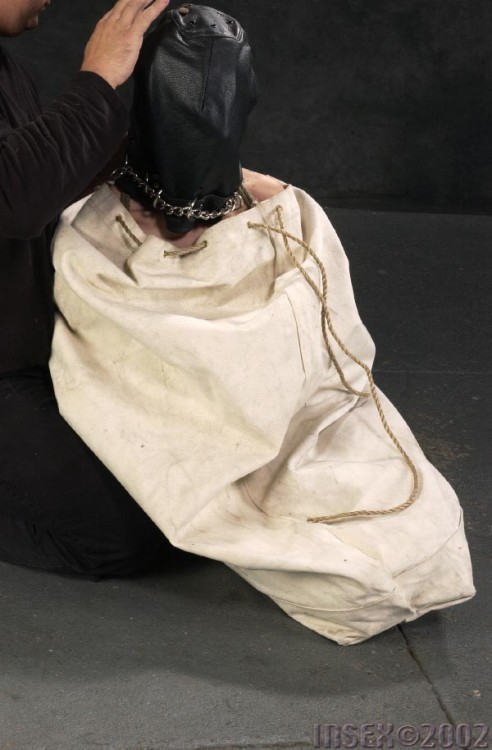 putmeinherplace:  I find layered bondage quite fascinating. Here, we have a mummy wrap, over which a leather muzzle is applied, followed by a loose leather hood and a burlap sack, and a large cloth bag for the final suspension. Quite a treat.