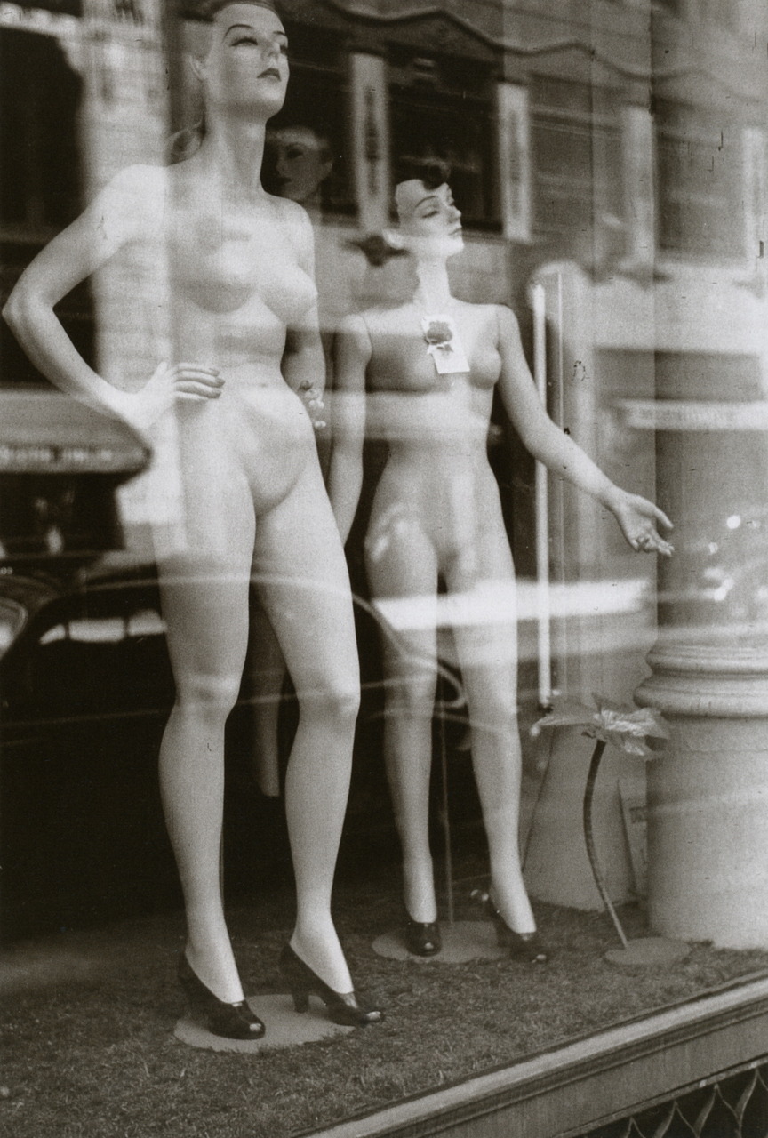 Two female mannequins stand undressed in a windowshop front in the 1940s. Photographed
