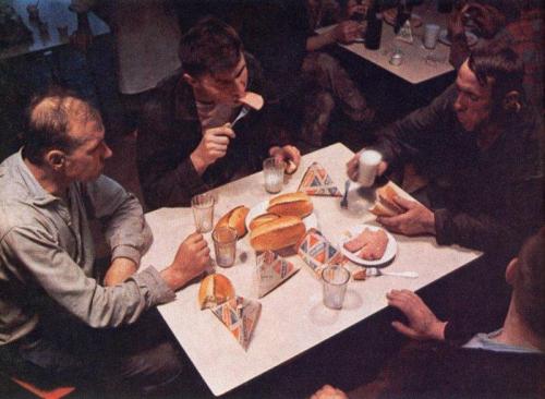 Soviet workers taking lunch with some kielbasa, bread and milk in those triangle boxes.