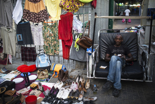 An African migrant, working as a street vendor, waits for customers in south Tel Aviv on July 17, 20