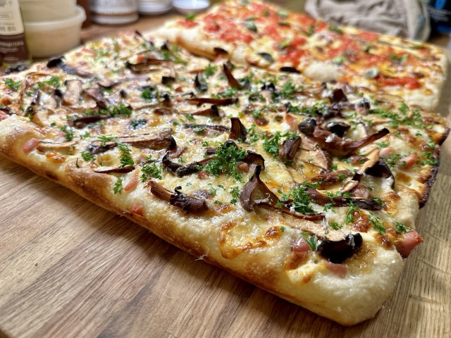 Two thin, rectangular pizzas: one with chanterelle mushrooms, one a margherita type of thing.