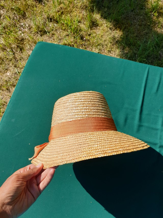 a straw hat from the side, looking vaguely bonnetlike